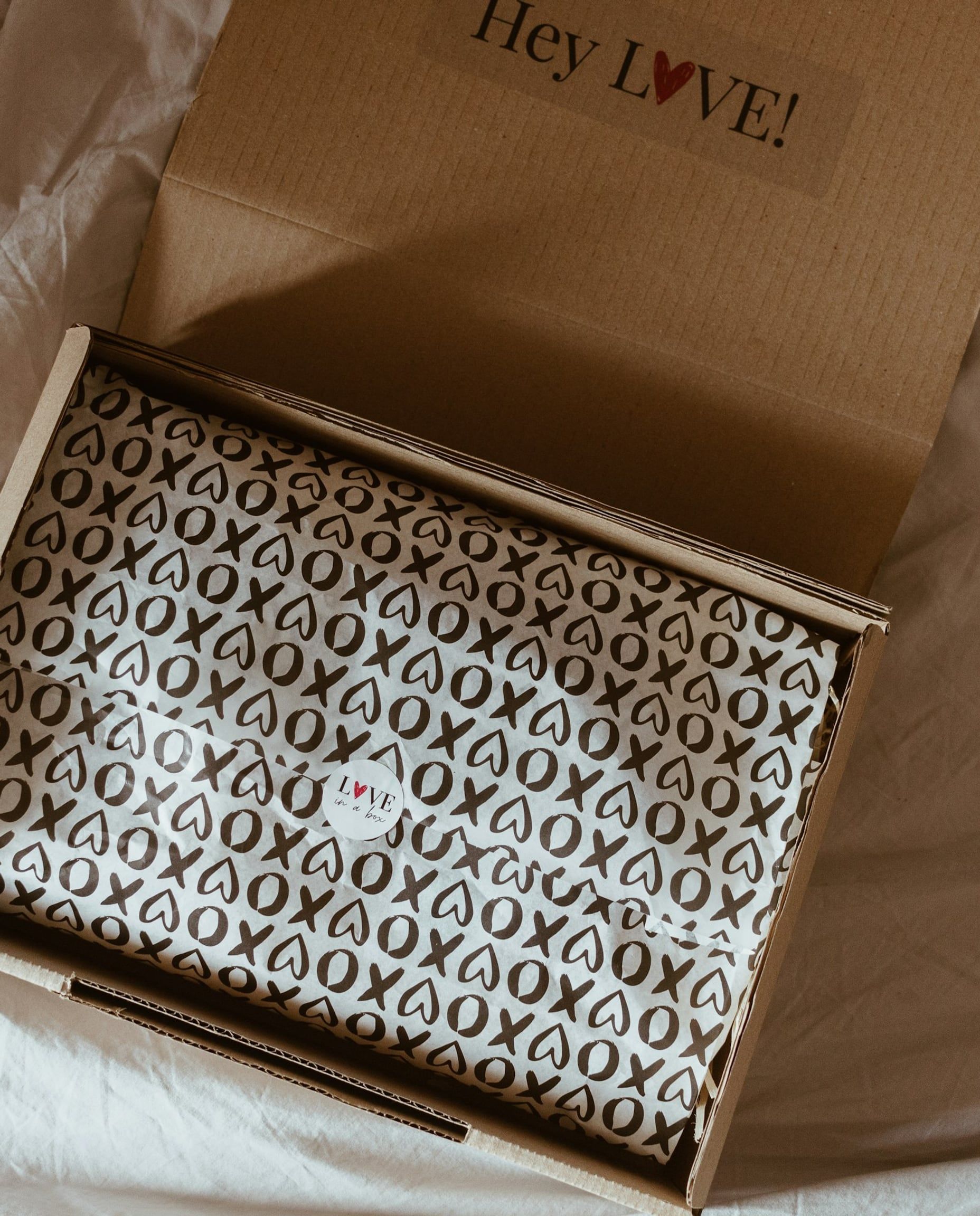An open subscription box lined with custom printed tissue paper and a “Hey LOVE!” card